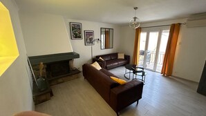 A living room with a fireplace, sofa, and a dining area. - Holiday Home 'Chez Brigitte' with Private Terrace, Wi-Fi and Air Conditioning (Chatillon sur marne)