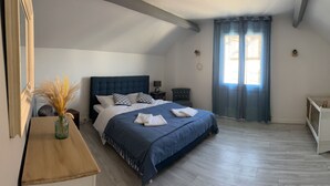 A bedroom with a bed, bedside tables, a nightstand, a crib, a window with curtains, and a vase with dried plants. - Holiday Home 'Chez Brigitte' with Private Terrace, Wi-Fi and Air Conditioning (Chatillon sur marne)