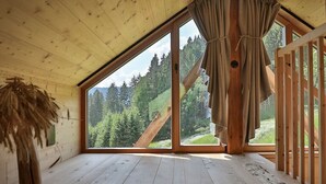 Uma cabana com uma janela grande, paredes de madeira e um deck de madeira.
