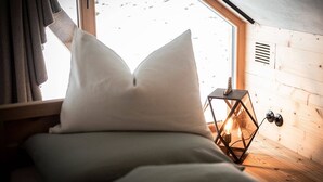 Um quarto de cabana acolhedor, com cama, janela com cortinas, um candeeiro e paredes de madeira.