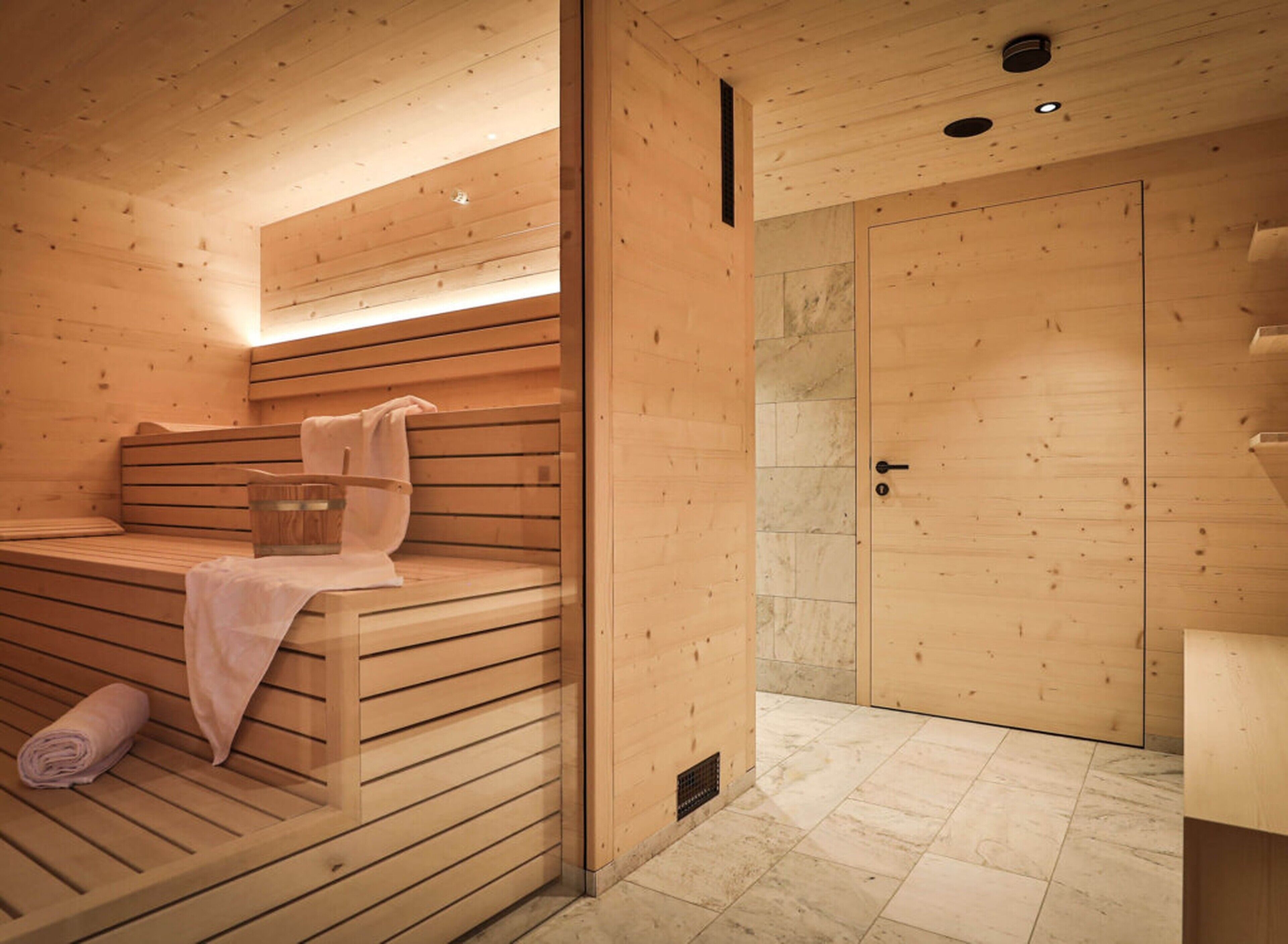 Eine Holzsauna mit Bänken, einem Handtuch und einer Tür.