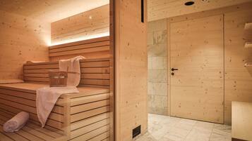 Eine Holzsauna mit Bänken, einem Handtuch und einer Tür.