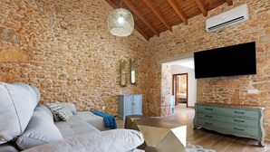 A stone-walled room with a sofa, a coffee table, a TV, and a cabinet. - Casa Rural Berrenda with Sea Views, Private Terrace, and Wi-Fi (Tiscamanita)