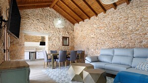 A rustic stone interior with a dining area, sofa, and unique geometric coffee table. - Casa Rural Berrenda with Sea Views, Private Terrace, and Wi-Fi (Tiscamanita)
