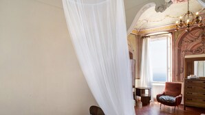 Una camera da letto con un letto, una sedia, una cassettiera e una finestra vista.