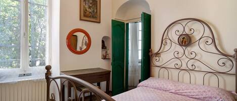 A bedroom with a bed, a window, a mirror, and a door.
