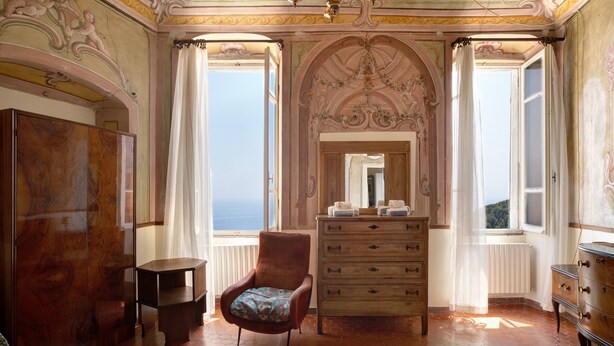Una stanza con un grande specchio, mobili in legno, una sedia e ampie finestre con vista.
