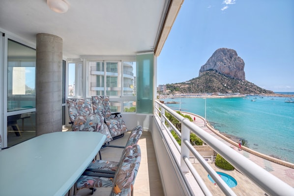 Un balcon avec une table et des chaises, une vue sur la mer et une formation rocheuse remarquable.