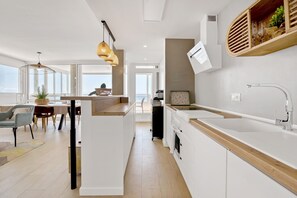 Une cuisine moderne avec des meubles blancs, un plan de travail en bois et un four encastré.