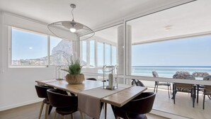 Ein Essbereich mit Meerblick, großen Fenstern und einer modernen Deckenleuchte.