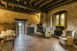 A rustic stone interior with a fireplace, wooden beams, and a stone wall.