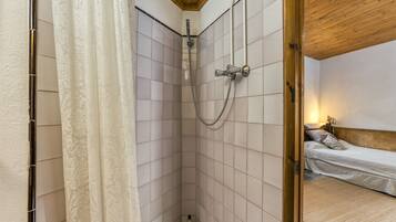 Une petite pièce compacte avec une douche, un lit et un plafond en bois.