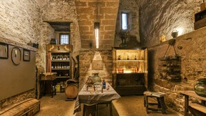 A rustic cellar with stone walls, wooden furniture, and shelves of bottles. - Castle 'Castell De Palau Sator' with Mountain View, Wi-Fi and Air Conditioning (Palau-sator)