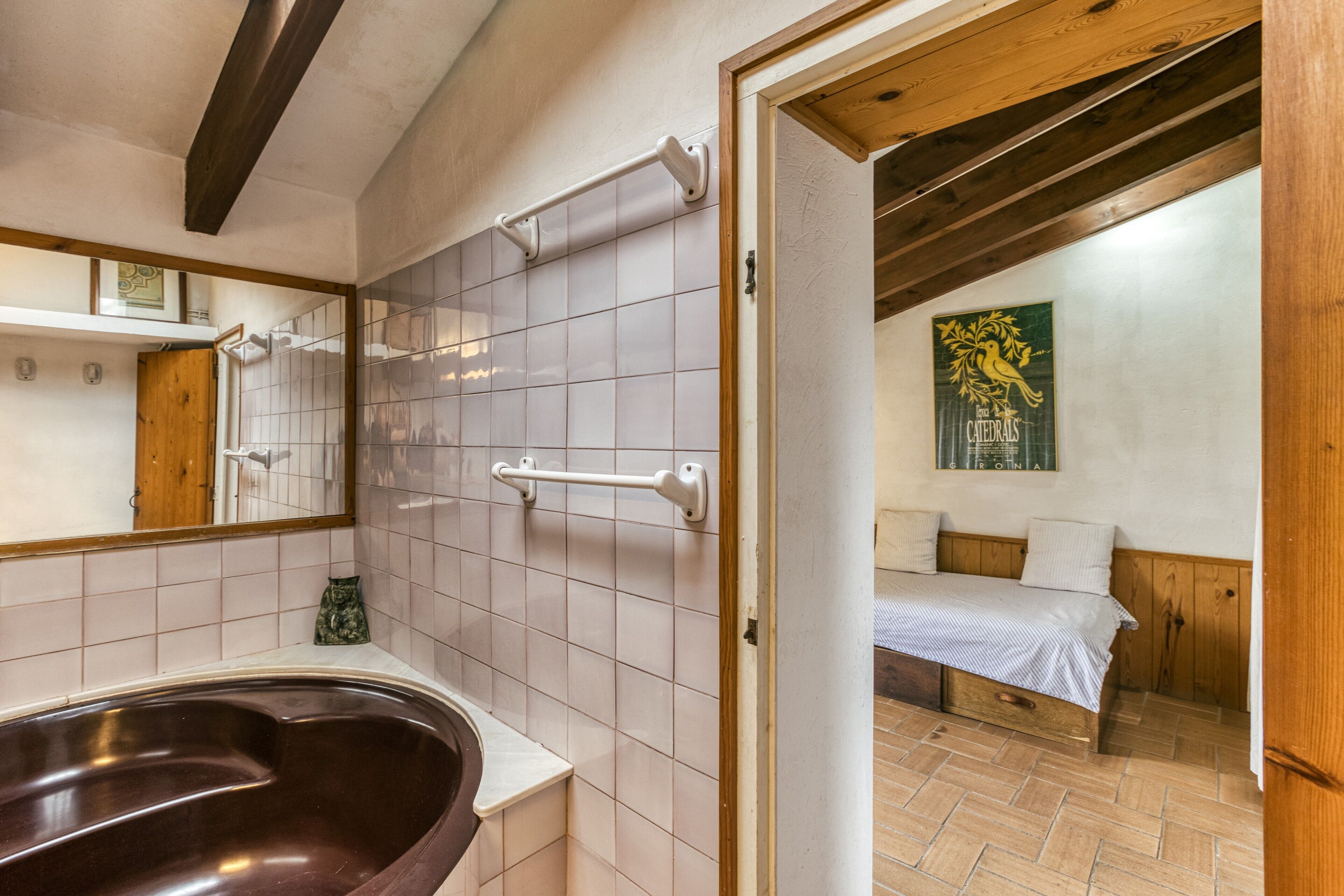 A bathroom with a bathtub, a mirror, and a wooden ceiling.