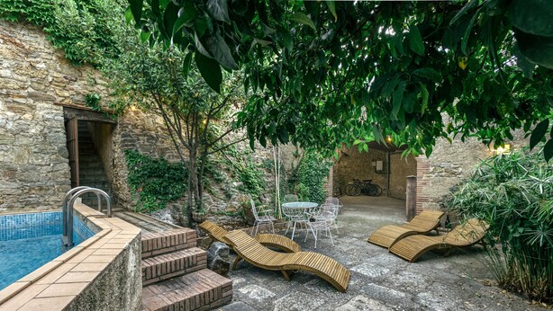 A stone building with a swimming pool, wooden loungers, and a table with chairs. - Castle 'Castell De Palau Sator' with Mountain View, Wi-Fi and Air Conditioning (Palau-sator)