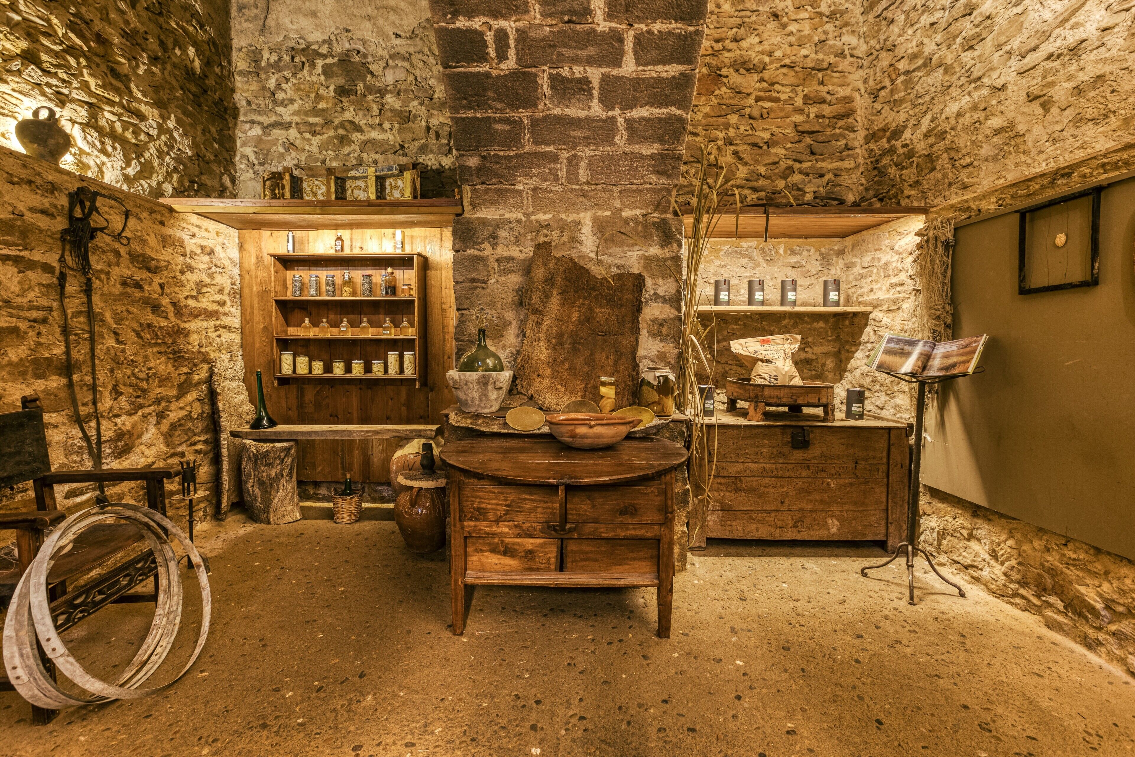 Een rustiek interieur met stenen muren, houten meubels en planken vol diverse objecten.