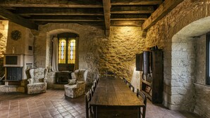 A stone-walled room with a long wooden table and chairs, a fireplace, and a stained glass window. - Castle 'Castell De Palau Sator' with Mountain View, Wi-Fi and Air Conditioning (Palau-sator)