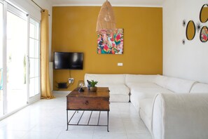 A living room with a sofa, a coffee table, a television, and a wall with artwork.