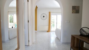 Une pièce spacieuse aux murs blancs, dotée d’un plancher en bois et d’un grand miroir.