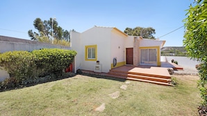 Uma casa térrea com um pequeno jardim frontal, uma porta e uma janela.