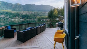 A deck with wicker furniture and a grill, overlooking a lake and forested mountains. - Emerald Haven Lakeside Paradise, Ultimate Retreat (Port Angeles)