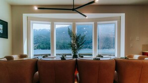 A dining area with a view of a lake and mountains through large windows. - Emerald Haven Lakeside Paradise, Ultimate Retreat (Port Angeles)