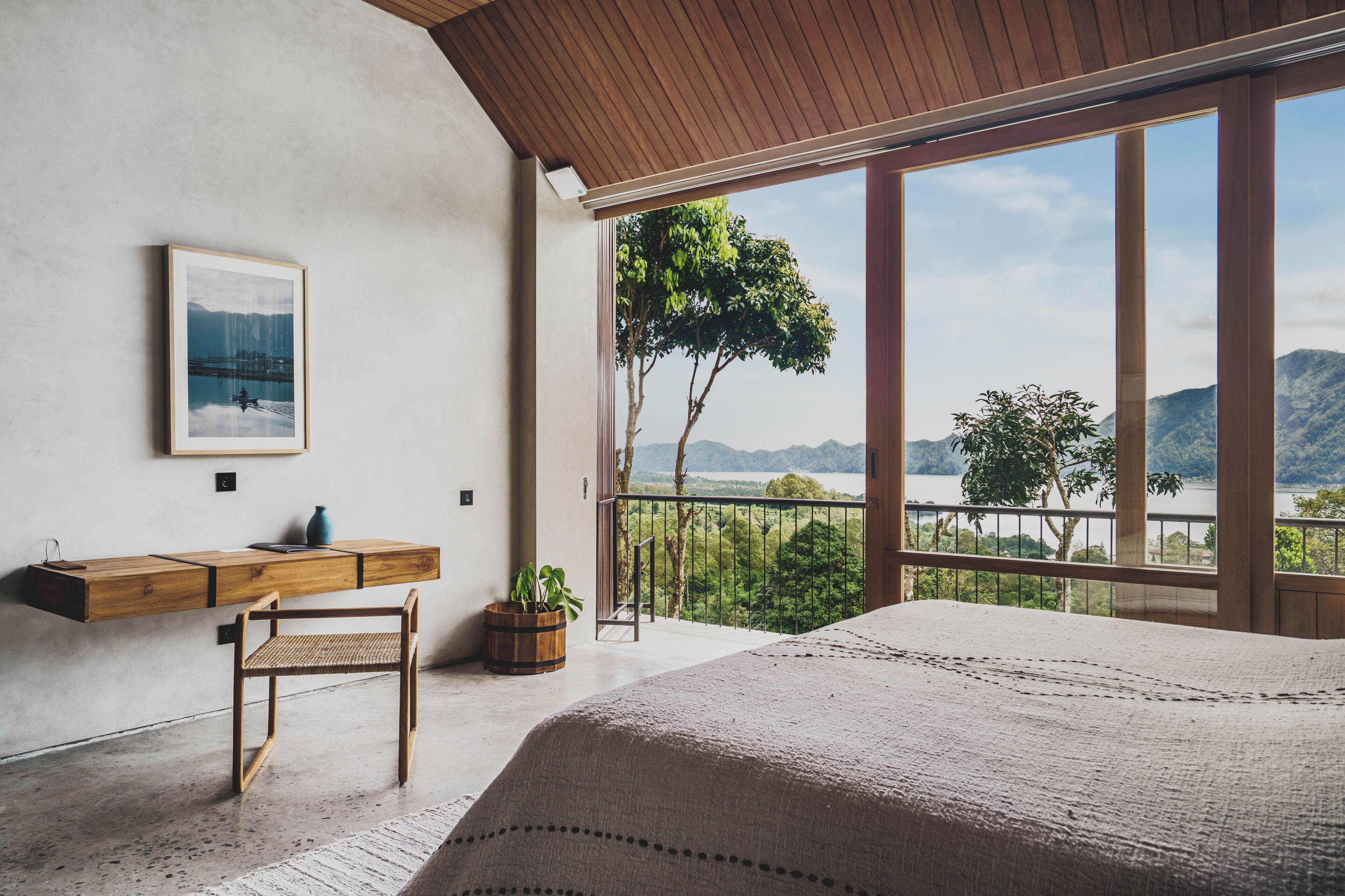 Ein Schlafzimmer mit großem Fenster, einem Holztisch, einem Stuhl und einem Bett.