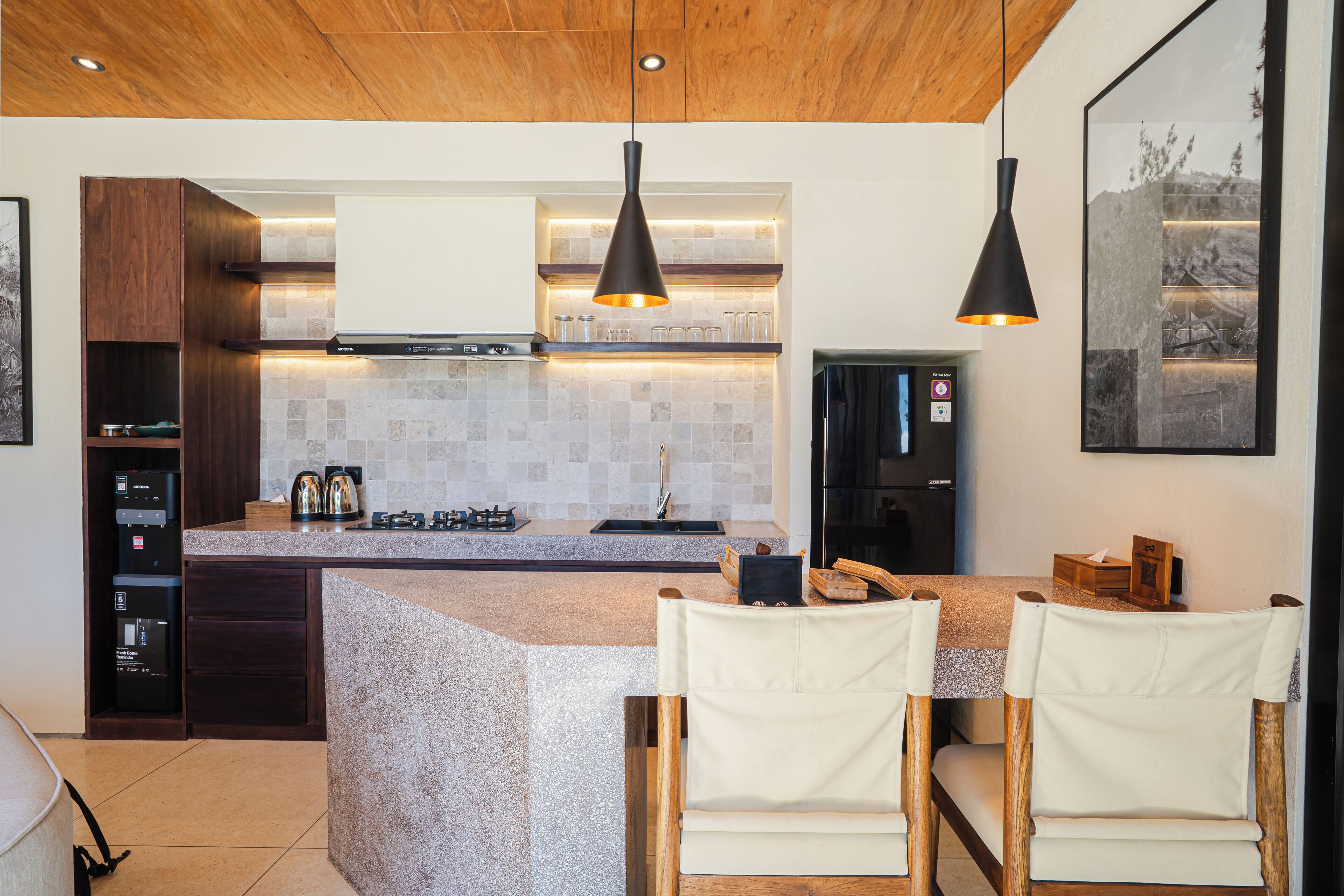 A modern kitchen with a granite countertop, wooden cabinets, and pendant lighting.