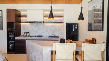 A modern kitchen with a granite countertop, wooden cabinets, and pendant lighting.
