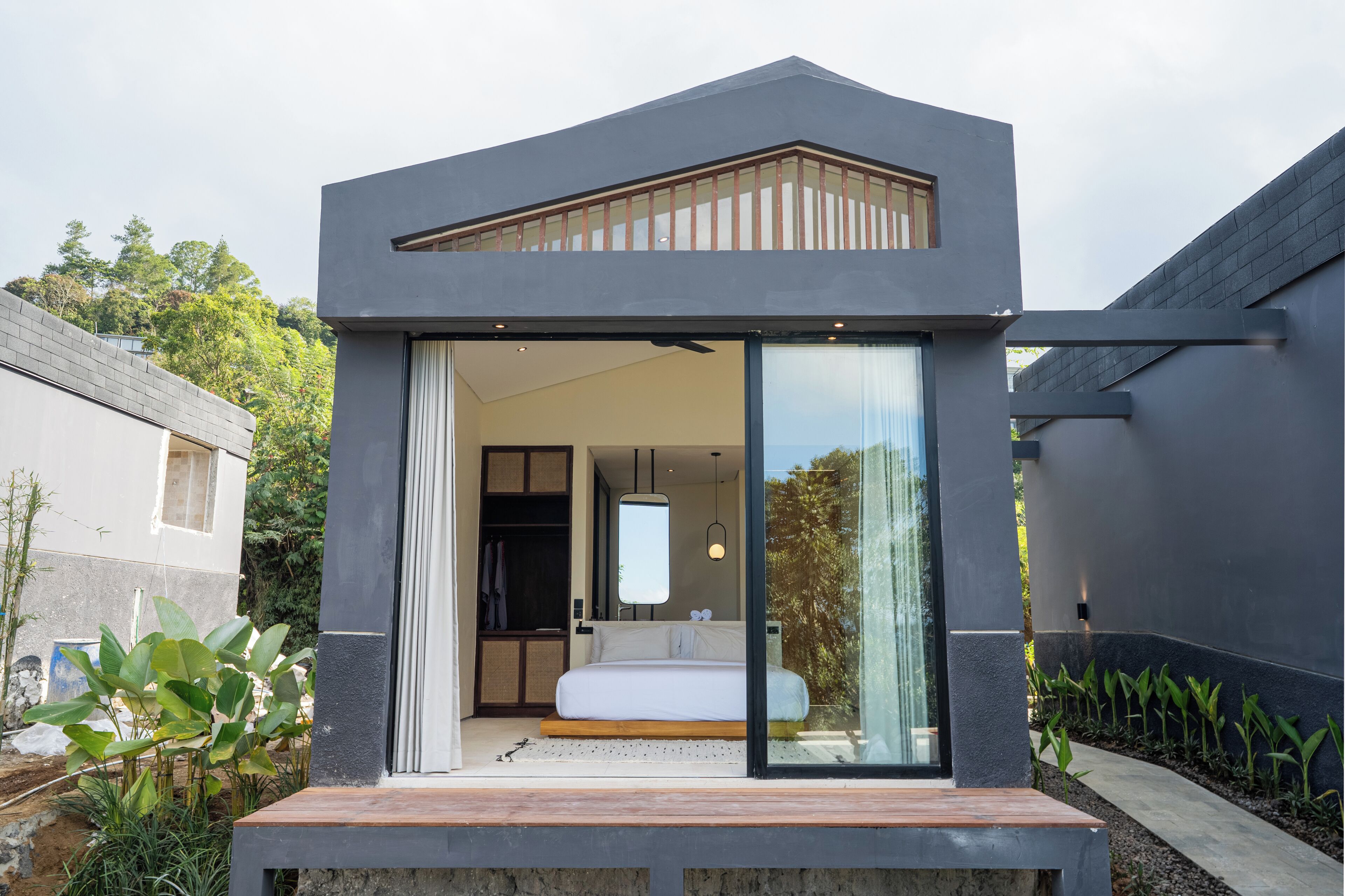 A modern bedroom with a large bed, sliding glass doors, and a view of the outdoors.