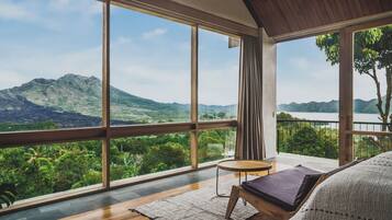 Un dormitorio moderno con ventanas amplias que dan a vistas de montañas y vegetación.
