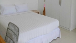 Un dormitorio con cama, armario, ventilador de techo y mesita de noche.