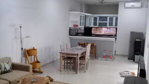 Una sala de estar moderna con un sofá, una mesa de centro y un comedor con sillas. Se ve un ventilador de techo e iluminación empotrada.