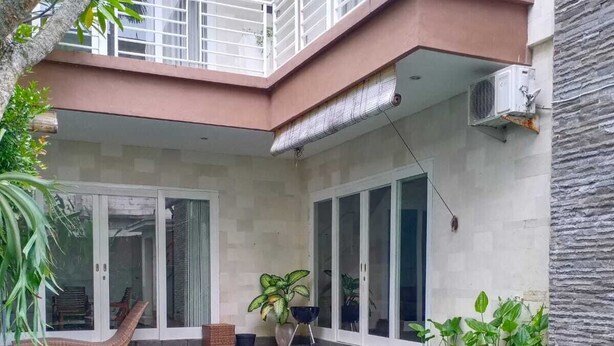 Un edificio residencial moderno con piscina, grandes puertas correderas de vidrio y un balcón con barandilla.
