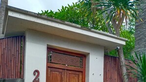 Un edificio de dos pisos con una puerta de madera grande, el número '2' en la pared y un pequeño porche.