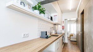 A modern kitchen with white brick backsplash, wooden countertops, and a built-in oven. - Apartamento Primavera (Parede)