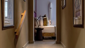 Een trap die leidt naar een slaapkamer met een bed, kussens en een bedlamp.