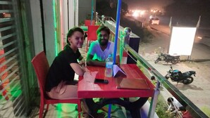 Two people seated at a table with a laptop, a bottle, and a smartphone on it. - Ugte Hotel (Rishikesh)