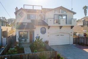 A two-story house with a garage, a balcony, and a small patio area with plants. - Oceanview Family Playground (Santa Cruz)