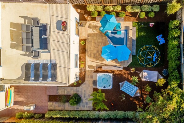 An aerial view of a backyard with a patio, seating area, hot tub, and a play structure. - Oceanview Family Playground (Santa Cruz)
