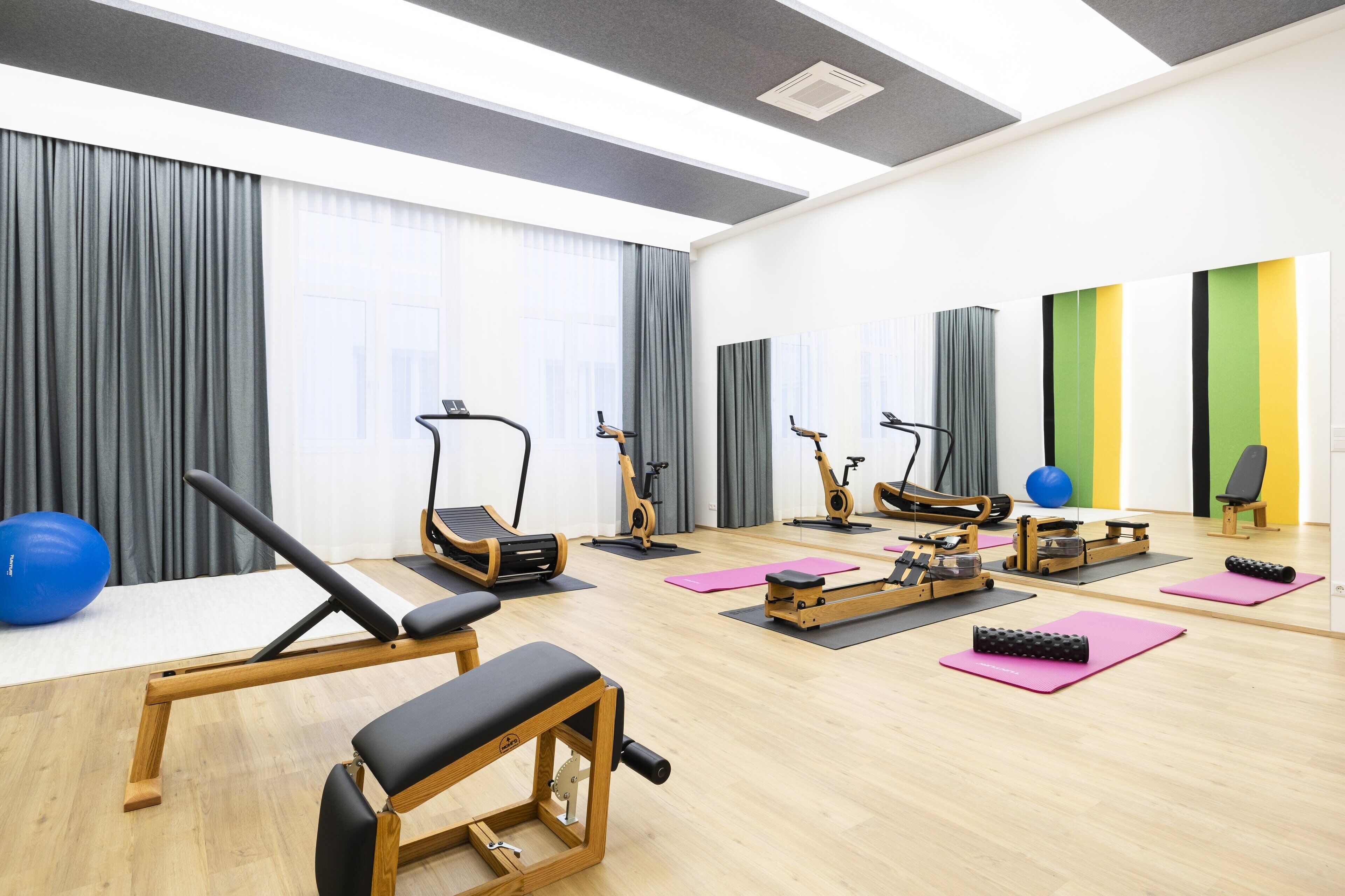Ein Fitnessraum mit Trainingsgeräten, Yogamatten und einem blauen Trainingsball.