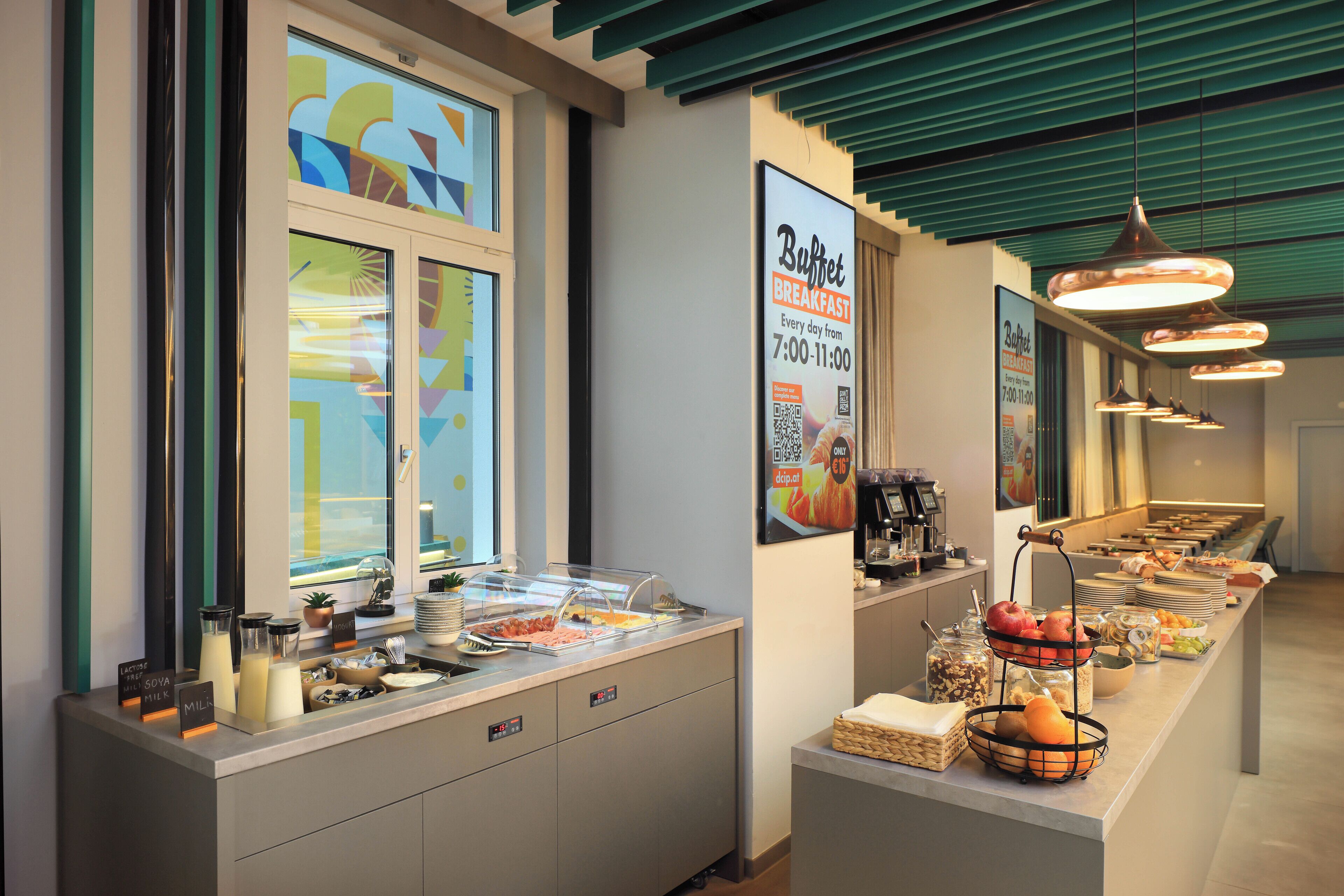 A buffet breakfast setup with a variety of food items and a sign indicating breakfast hours.