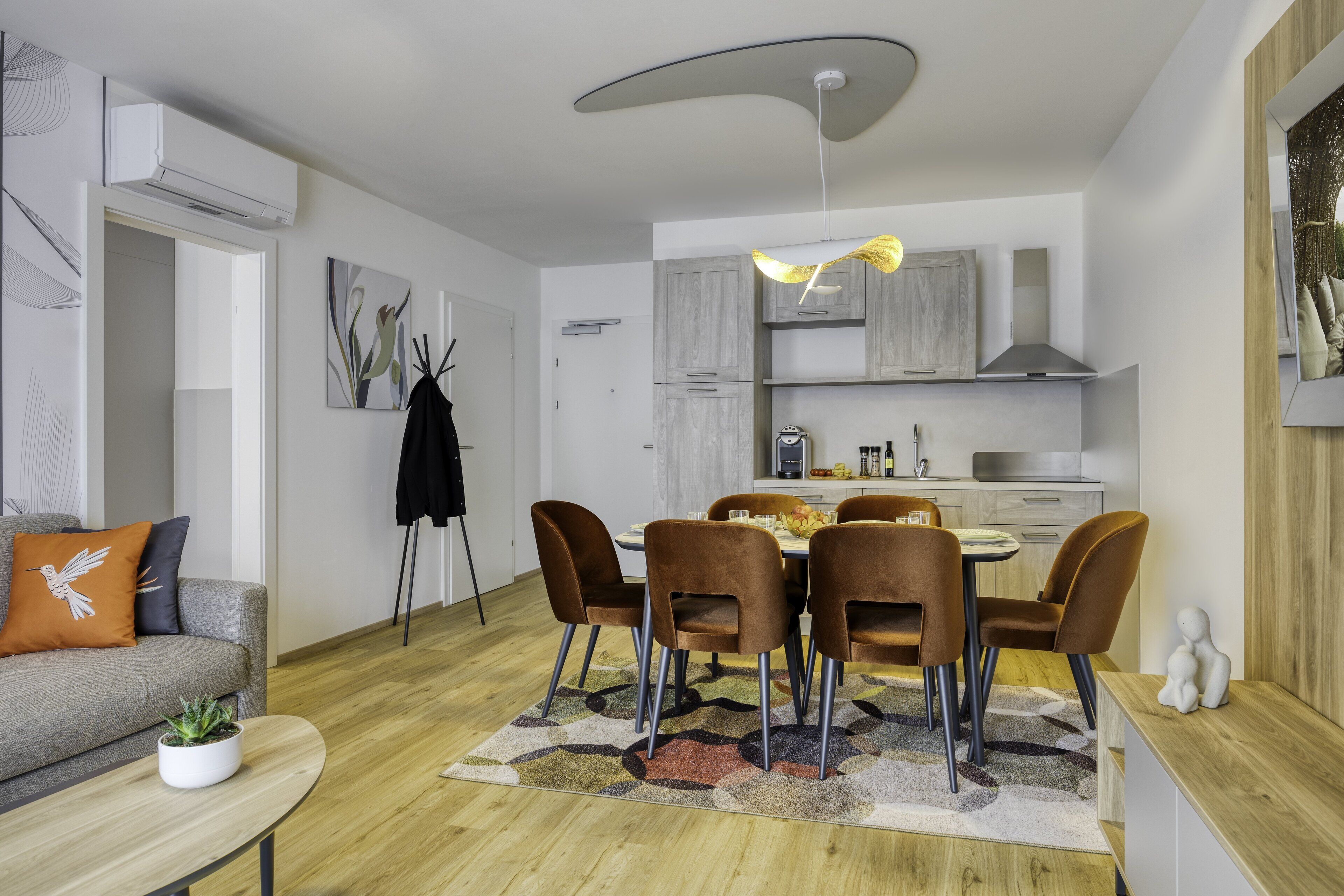 Un salon moderne avec un canapé gris, une table basse et un coin repas comprenant des chaises et une table en bois.