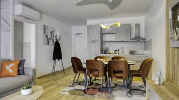 Un salon moderne avec un canapé gris, une table basse et un coin repas comprenant des chaises et une table en bois.