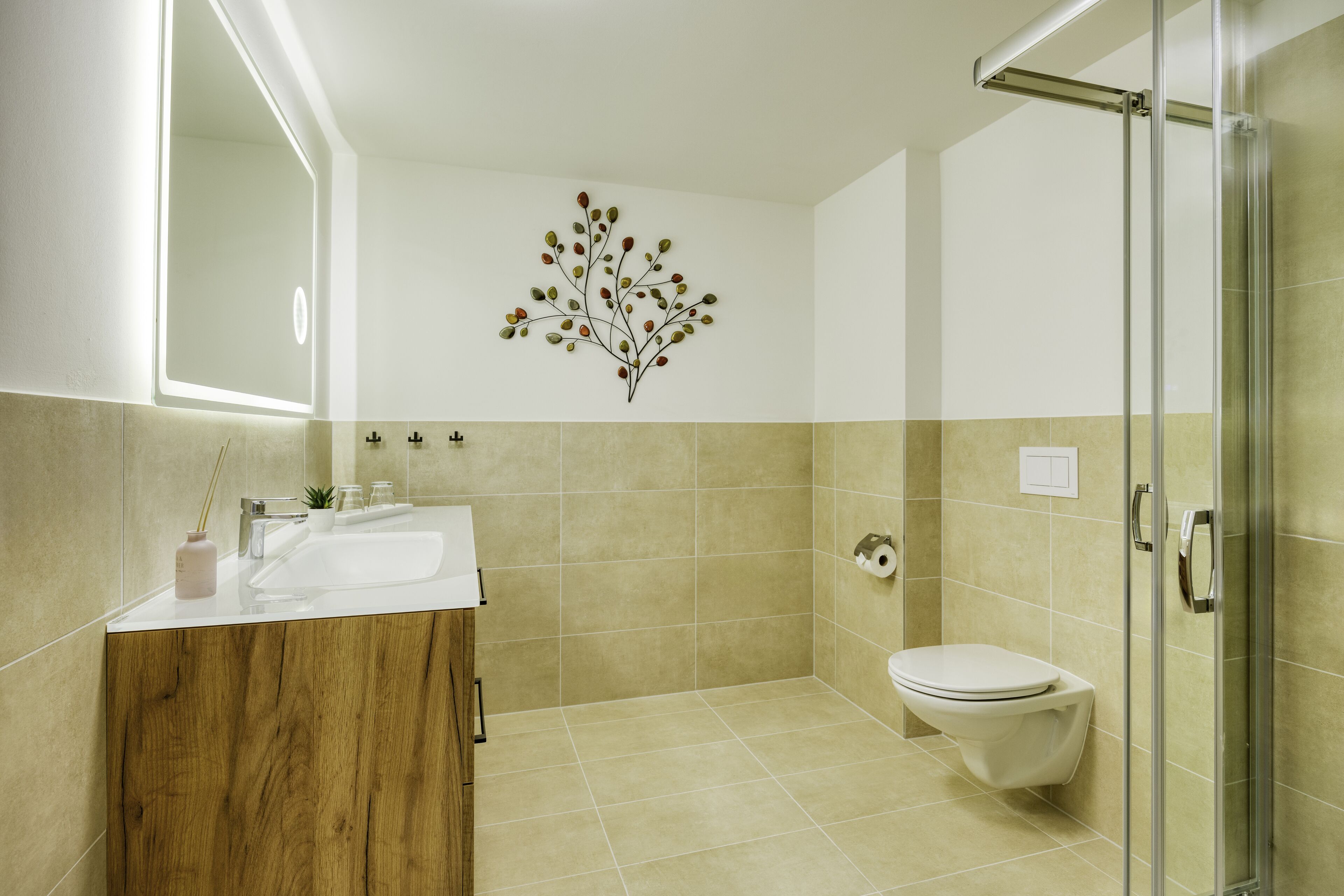 A modern bathroom with a wooden vanity, a glass shower enclosure, and a wall-mounted toilet.