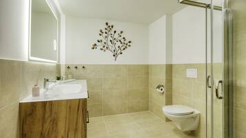 A modern bathroom with a wooden vanity, a glass shower enclosure, and a wall-mounted toilet.