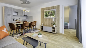 Una sala de estar moderna con comedor, piso de madera y un ventanal con vista a árboles.