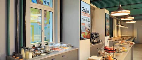 A buffet breakfast setup with a variety of food items and a sign indicating breakfast hours.