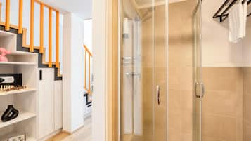 A modern bathroom with a glass-enclosed shower, a white bathtub, and a wooden staircase.
