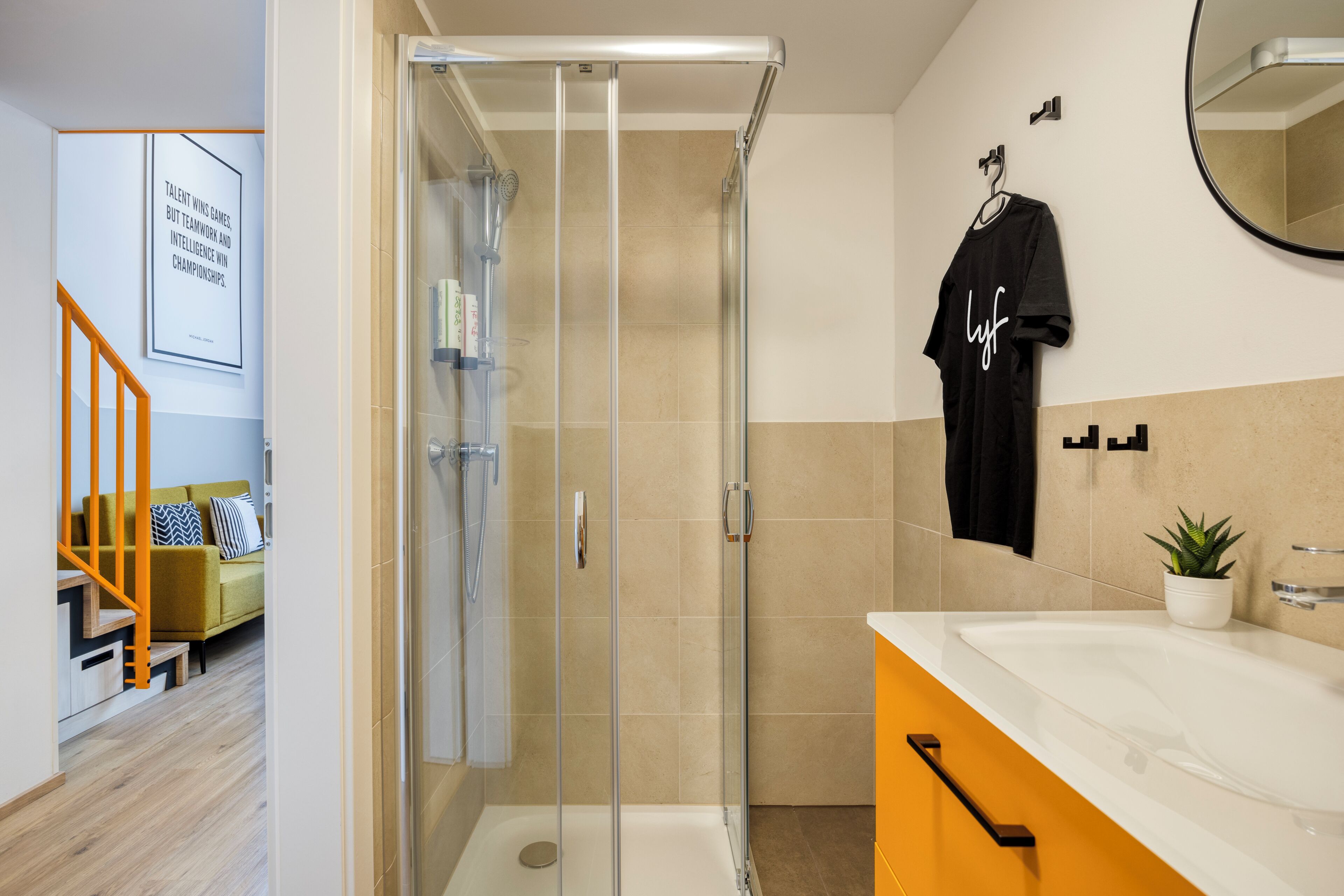 A modern bathroom with a glass shower enclosure, a white sink, and a black towel hanging on the wall.